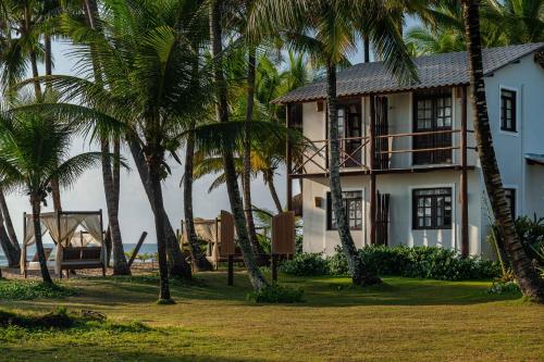 a white house with palm trees in front of it at Rumah Pousada in Barra Grande