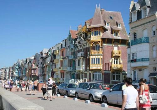 eine Gruppe von Menschen, die eine Straße mit Gebäuden entlanggehen in der Unterkunft Appartement calme à 300 m de la plage-centre ville - Quiet appartment 300 m near city and beach in Mers-les-Bains