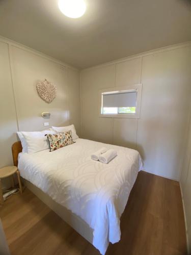 a bedroom with a white bed with a window at Lorsens on the River - Shoalhaven Heads in Shoalhaven Heads