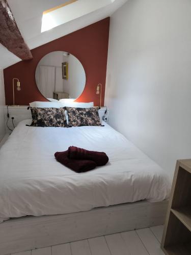 une chambre avec un grand lit blanc avec un miroir dans l'établissement Petite Maison centre du village, à Noyers-sur-Serein