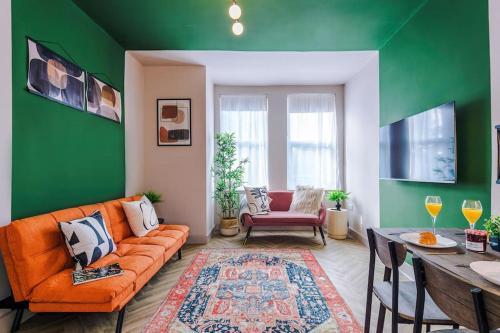 a living room with an orange couch and a green wall at Modern 4-Bedroom in Manchester in Manchester