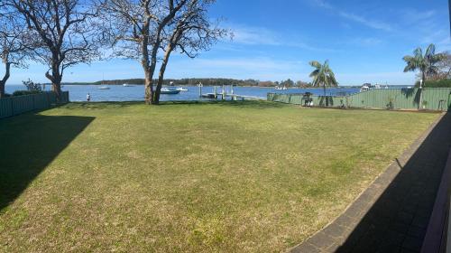 a grassy yard with a view of the water at Lorsens on the River - Shoalhaven Heads in Shoalhaven Heads