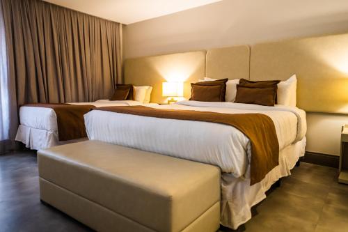 a hotel room with two beds and a ottoman at Oceana Atlântico Hotel & SPA in João Pessoa