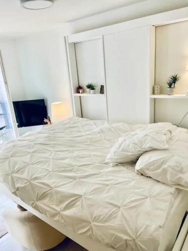un grand lit blanc dans une chambre avec une fenêtre dans l'établissement Bel appartement pour un séjour touristique, à Paris