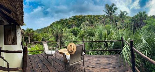 una terraza de madera con un sombrero y una silla. en Black Sand Hotel Boutique, en Zapotal