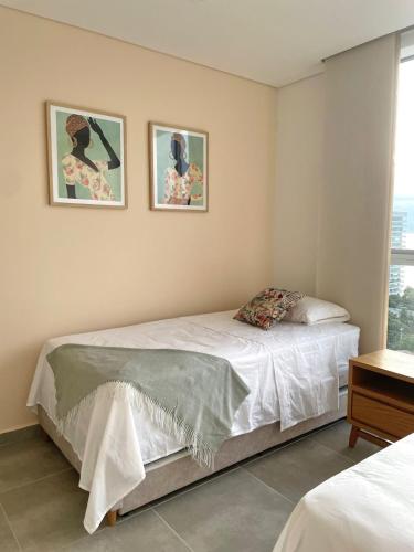a bedroom with a bed and two pictures on the wall at Salguero Suites - Playa Salguero - By INMOBILIARIA VS in Santa Marta