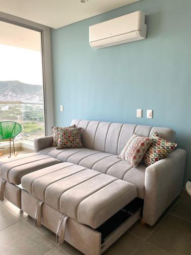 a large couch in a living room with a window at Salguero Suites - Playa Salguero - By INMOBILIARIA VS in Santa Marta