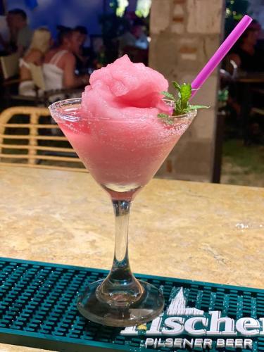 a pink drink in a martini glass on a table at Socrates Studios in Tigaki