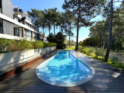 a swimming pool on a wooden deck next to a building at Departamento Moderno Premium con Piscina y Cochera in Pinamar