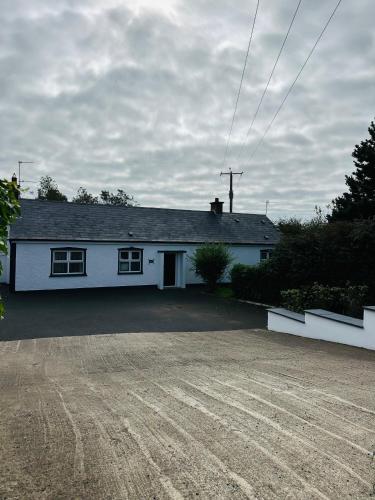 a white house with a driveway in front of it at Cloyfin Holiday Home in Cloyfin