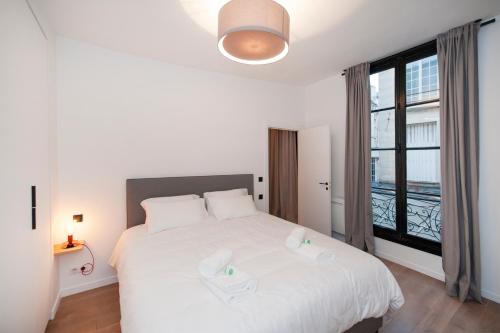 パリにあるPick A Flat's Apartment in Le Marais - Rue Sainte Croix de la Bretonnerieのベッドルーム(白いベッド1台、大きな窓付)