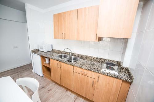 a kitchen with wooden cabinets and a sink at Pierre&Vacances Mallorca Portofino in Santa Ponsa