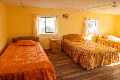 a hotel room with two beds and two windows at Pachamama Hospedaje & Restaurant Pitumarca in Checacupe