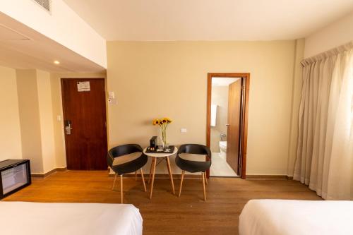 a hotel room with two beds and a table and chairs at Hotel Faranda Express Soloy and Casino, a member of Radisson Individuals in Panama City