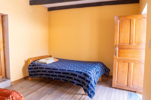 a small bedroom with a bed with a blue blanket at Pachamama Hospedaje & Restaurant Pitumarca in Checacupe