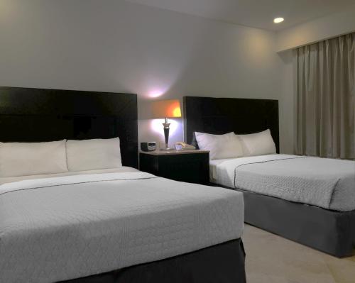 a hotel room with two beds and a lamp at Wyndham Garden Los Mochis Plaza Inn in Los Mochis