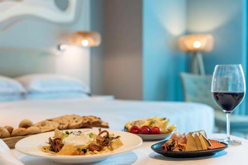 a table with two plates of food and a glass of wine at Hilton Santa Marta in Santa Marta