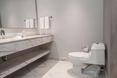 a white bathroom with a toilet and a sink at Hilton Santa Marta in Santa Marta
