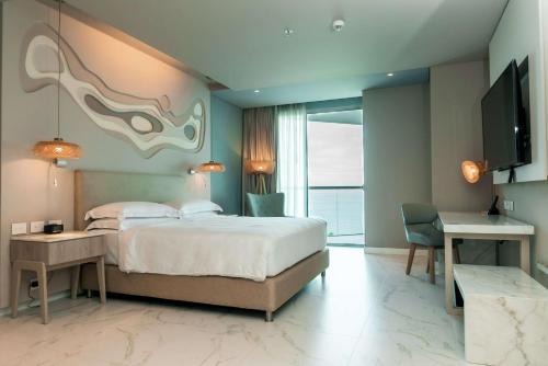 a bedroom with a bed and a desk and a television at Hilton Santa Marta in Santa Marta