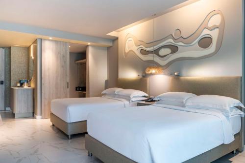 two beds in a hotel room with a painting on the wall at Hilton Santa Marta in Santa Marta