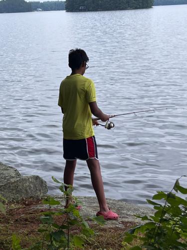 a young man standing on the edge of a lake fishing at Birkswyld waterfront cottage Mary Lake in Huntsville