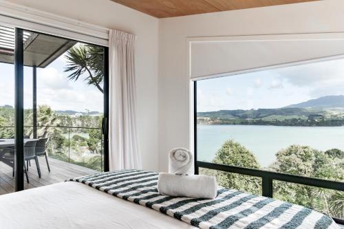 a bedroom with a bed and a large window at On Point House, Luxury design, Water Views in Raglan