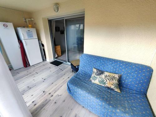 - un canapé bleu avec un oreiller dans l'établissement T2 Climatisé rénové avec Parking et Piscine pour 4 près de la mer - FR-1-607-205, au Cap d'Agde