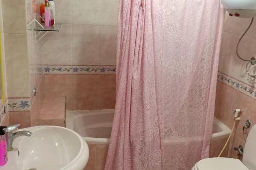 a bathroom with a sink and a pink shower curtain at Universal family apartment in Cairo