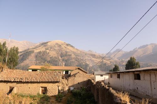 a group of houses in a village with mountains in the background at Pachamama Hospedaje & Restaurant Pitumarca in Checacupe