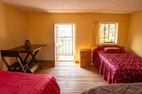 a bedroom with two beds and a desk and a window at Pachamama Hospedaje & Restaurant Pitumarca in Checacupe