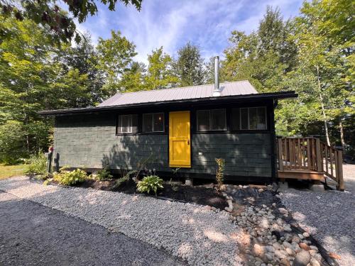 a tiny house with a yellow door on a gravel road at Birkswyld waterfront cottage Mary Lake in Huntsville