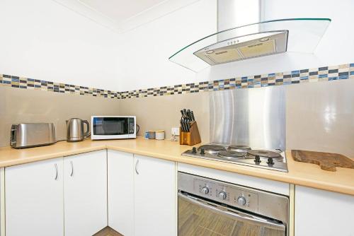 a kitchen with a stove and a microwave at Misty Mountain View - A Tree-lined Tropical Oasis in Lower Beechmont