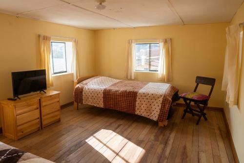 a bedroom with a bed and a tv and two windows at Pachamama Hospedaje & Restaurant Pitumarca in Checacupe