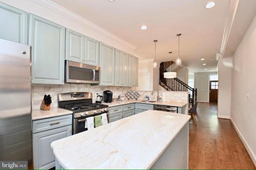 a kitchen with white cabinets and a marble counter top at Elegant 5BR home near Capitol Hill! Free Parking! in Washington, D.C.