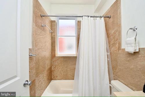 a white shower curtain in a bathroom with a window at Elegant 5BR home near Capitol Hill! Free Parking! in Washington, D.C.