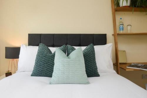 a white bed with green pillows on it at Wilson House - Camden in London
