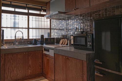 a kitchen with wooden cabinets and a black refrigerator at CraftFlat Asakusa House, Space to Live, Laugh, and Feel at Home in Tokyo