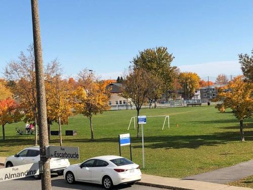 two cars parked in front of a park with a field at La maison de Gabriel in Quebec City