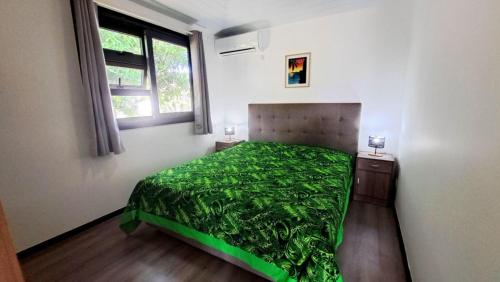 a bedroom with a green bed with a window at TAHITI - Mango Lodge Matie in Papara