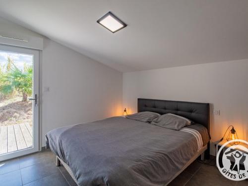 a bedroom with a large bed and a window at Gîte Moderne et Confortable Proche Cholet, Nantes et Puy du Fou, avec Terrasse et Près d'un Étang - FR-1-622-43 in La Renaudière