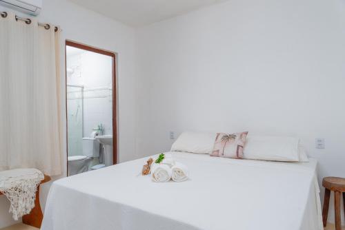 a white bedroom with a white bed and a mirror at Pousada Trilha do Mar in Praia do Frances