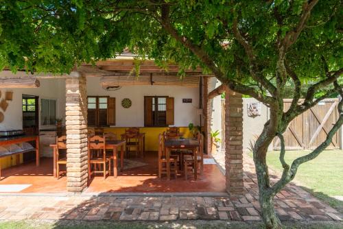 a patio with a table and chairs under a tree at Pousada Trilha do Mar in Praia do Frances