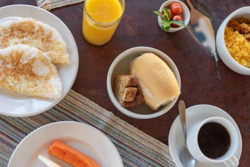 a table with plates of breakfast foods and a cup of coffee at Pousada Trilha do Mar in Praia do Frances