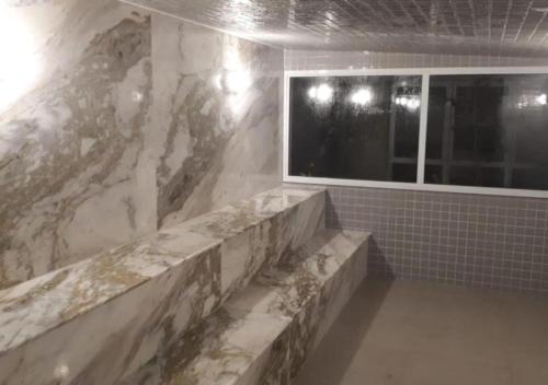 baño con pared de mármol y ventana en Portal das Palmeiras 2, en Ubatuba