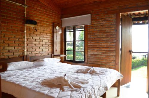 a bedroom with a large bed in a brick wall at Pousada Alto Pirapitinga in Resende