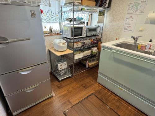 a kitchen with a stainless steel refrigerator and a sink at 和良和楽の宿 in Hikone