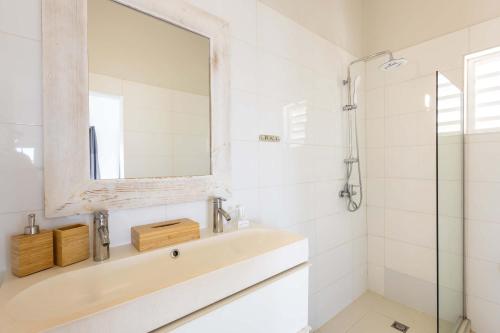 a white bathroom with a sink and a mirror at Artiko Luxury Suites - Jan Thiel in Jan Thiel