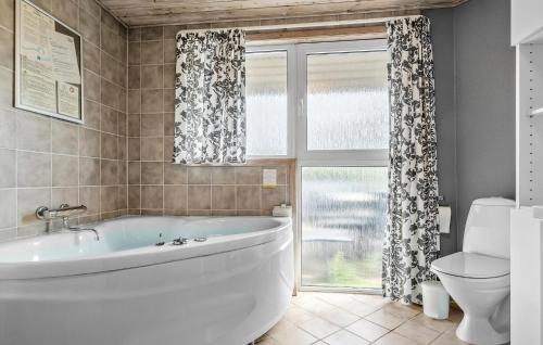 a bathroom with a tub and a toilet and a window at Awesome Home In Hejls With Sauna in Hejls