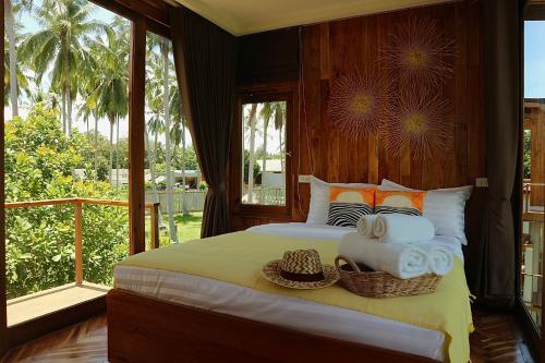 a bedroom with a bed with towels and a balcony at บ้านพราวพร้าว Baan Proud Proud in Khanom