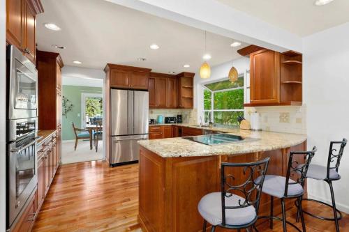 una cucina con armadi in legno e un'isola con sgabelli da bar di Cozy Redmond Retreat- Shared Home near Parks and Attractions a Redmond